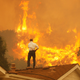 A man on a rooftop looks at approaching flames from the Springs fire in May 2013 near Camarillo, California.